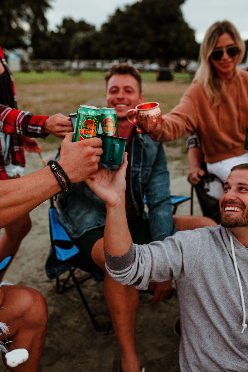 People sitting together with mugs and Reed's Extra Ginger Beer cans.