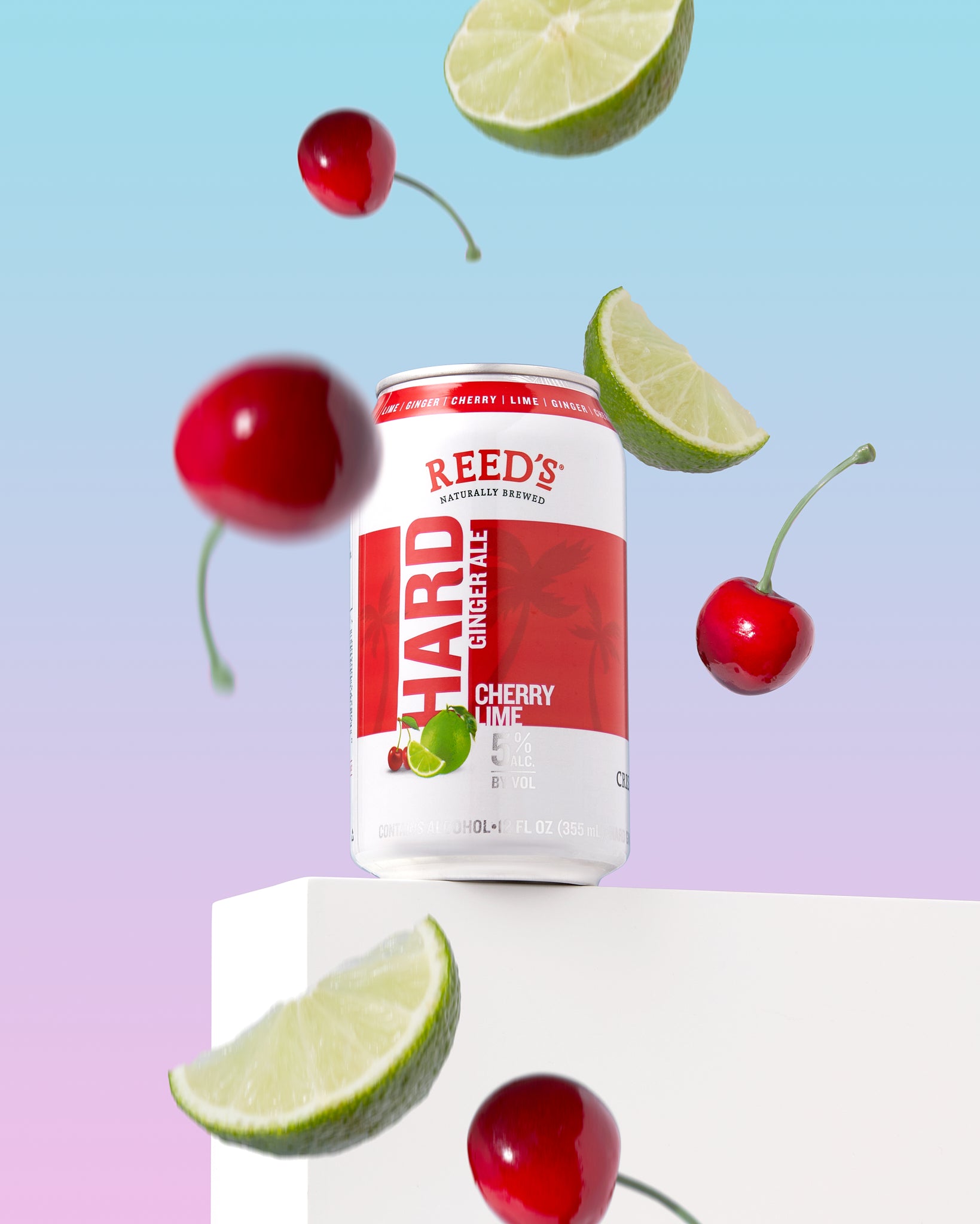 Reed's Hard Cherry Lime Ginger Ale next to some cherries and limes on a light blue background.
